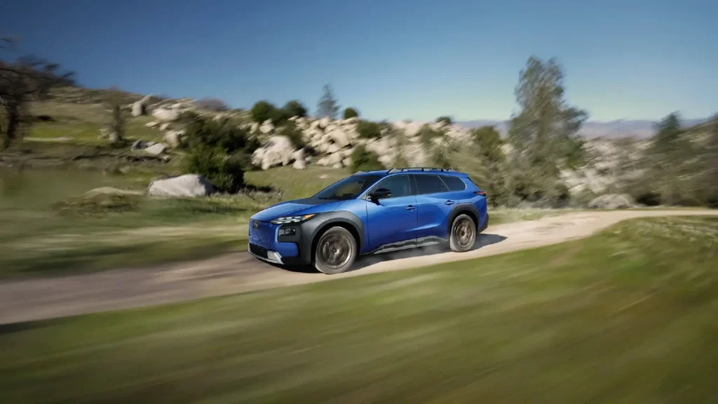 Blå SUV kjører raskt på grusvei i naturen.