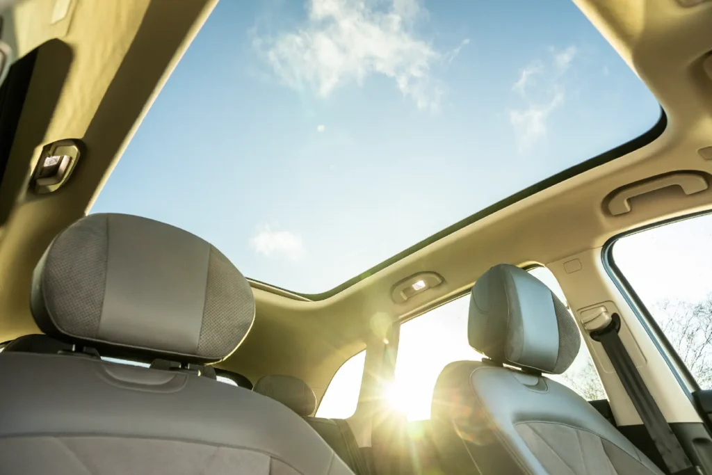 Bilinnredning med to seter og stort soltak som slipper inn sollys.