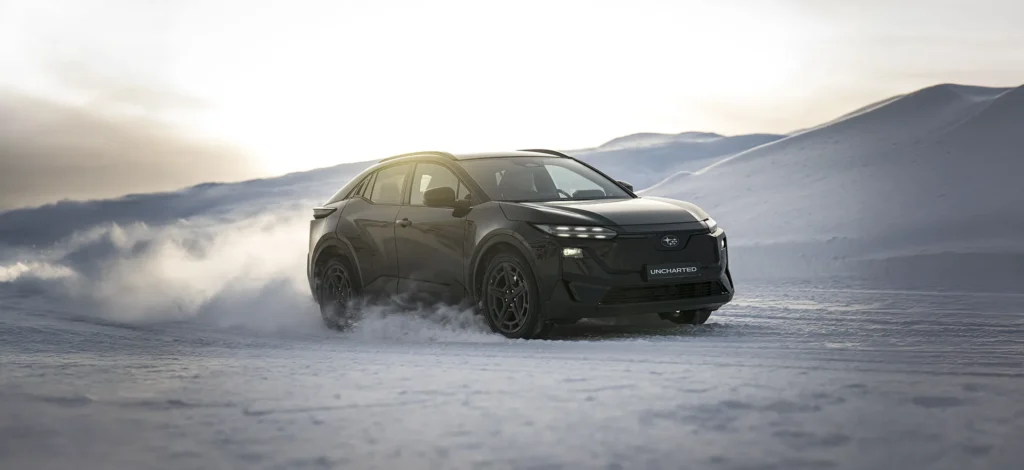 Svart SUV kjører i snødekt landskap med store snødriv.