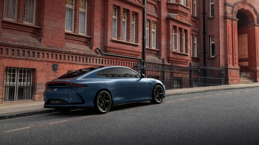 Blå MG IM6 sedan parkert ved rød murbygning i byen.